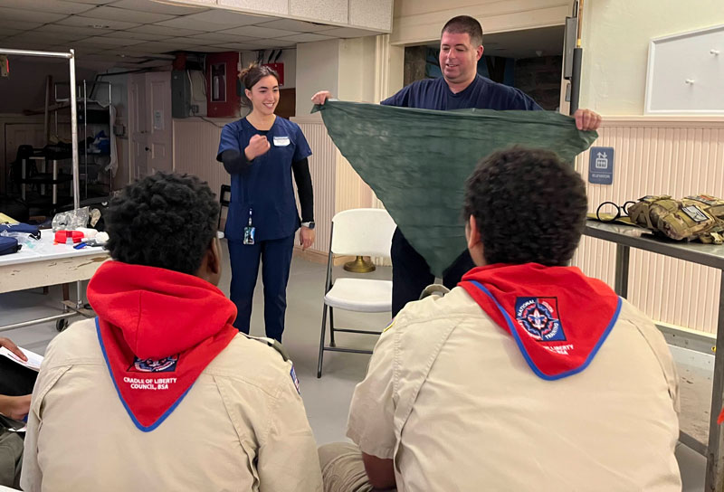 Scout leader and medical student demonstrate medical techniques for young scouts