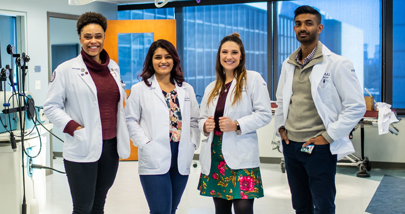 PCOM DO students pose in their white coats. Doctoral students from the nation's medical schools could be used to help increase COVID vaccination efforts.