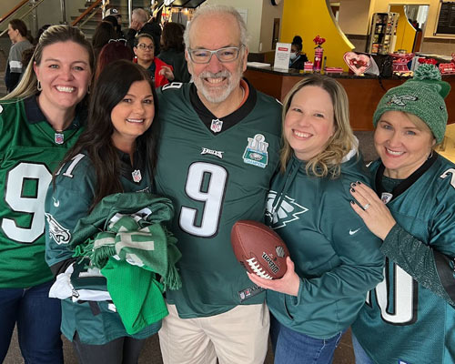 Dr. Jay Feldstein poses with PCOM staff during the filming of the PCOM vs. KCU Super Bowl Challenge video