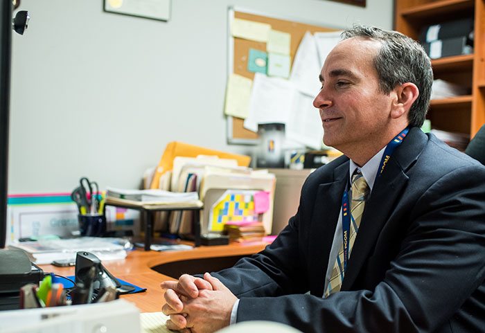 Scott Glassman, PsyD, director of positive psychology programs, smiles at his computer during an online class.