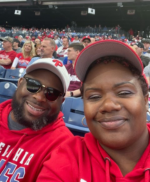 Terri Allen and her husband David smiling in the stands of a Phillies baseball game