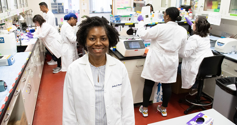 Dr. Hatcher in foreground of laboratory with students working in background