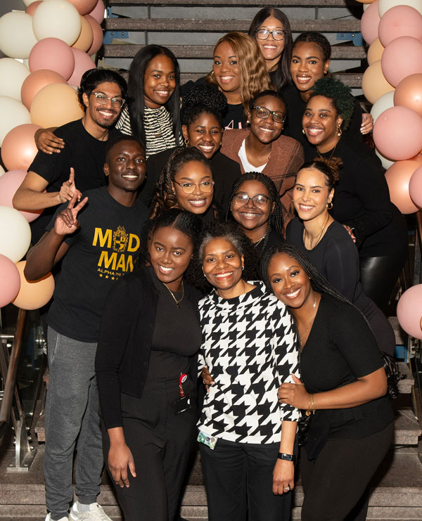 Dr. Hatcher posing on stairway surrounded by students