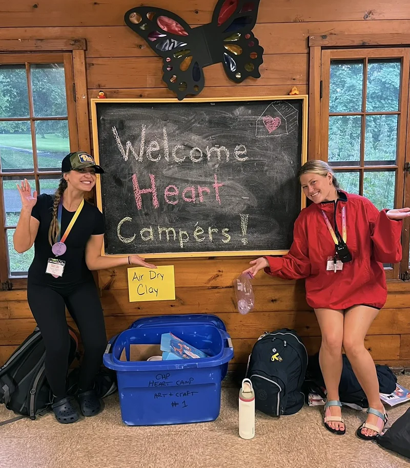 Med student Elexa White (DO '27) poses in front of a welcome sign for campers at Camp Heart near Pittsburgh