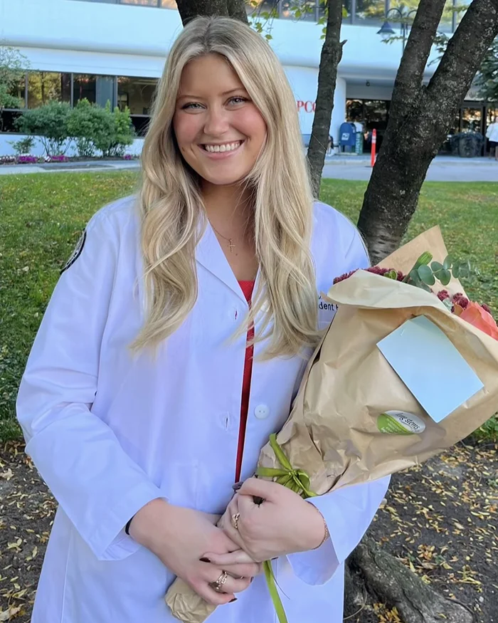 Osteopathic medical student Elexa White (DO '27) smiles with flowers after PCOM's white coat ceremony