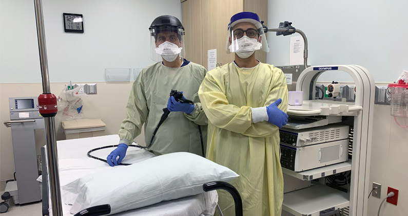 Medical student Justin Canakis (DO '21) wears PPE and stands next to his father in an endoscopy patient care room