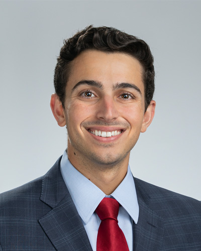 Osteopathic medical student Justin Canakis smiling in a suit and tie.