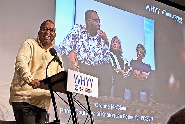 Oronde McClain stands at podium during presentation