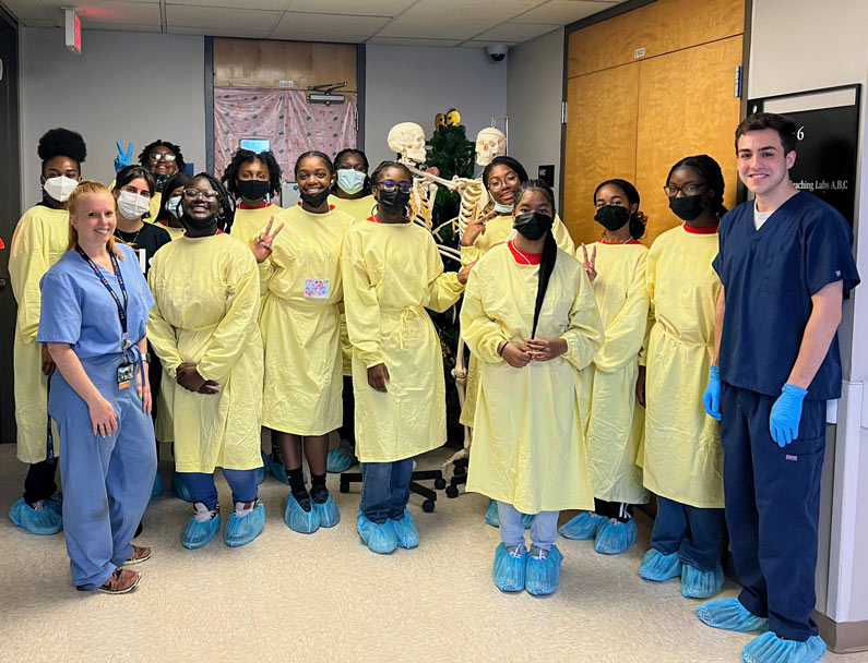 Girls Inc. Eureka! participants dress in scrubs during a PCOM lab visit