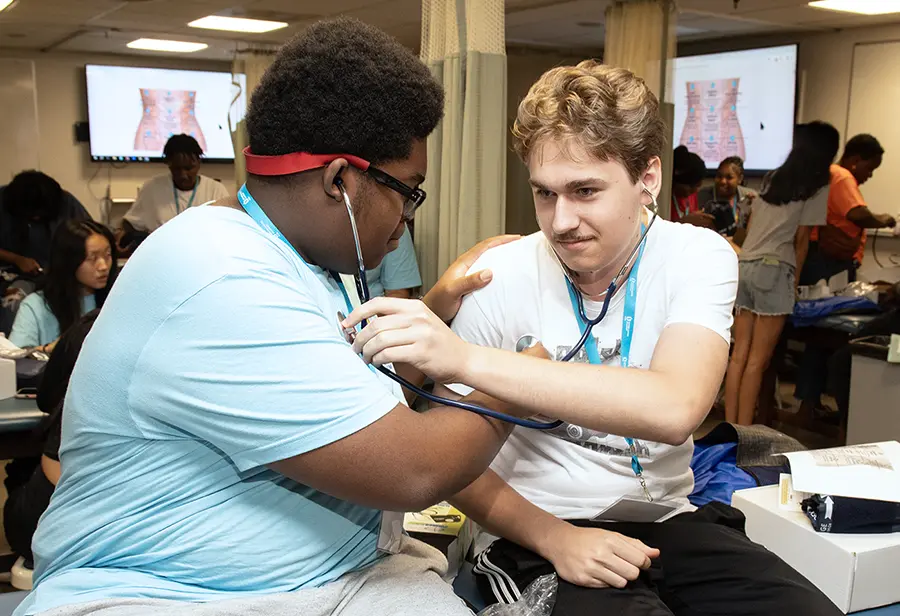 High school students use stethoscopes to listen to each other's heartbeats during a learning exercise at PCOM Opportunities Academy