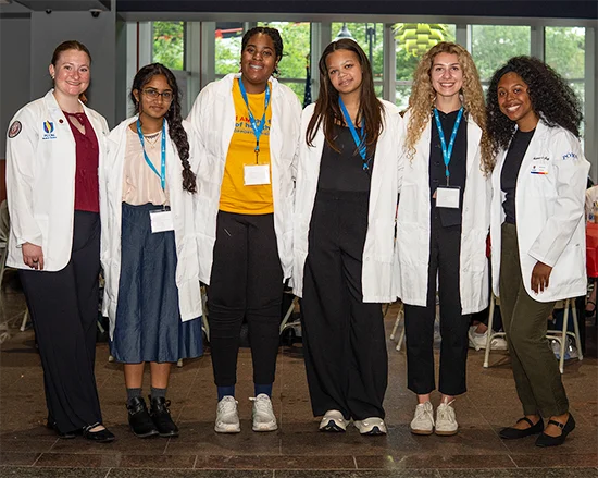 High school students standing together while wearing white medical lab coats