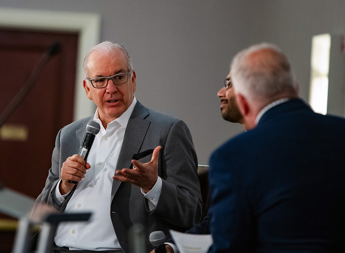 PCOM's Jay Feldstein, DO, holds a microphone and speaks with two panel members