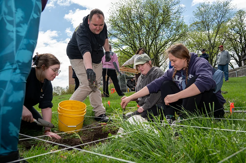 Students gather around mock dig site during a PCOM Forensic Medicine program course