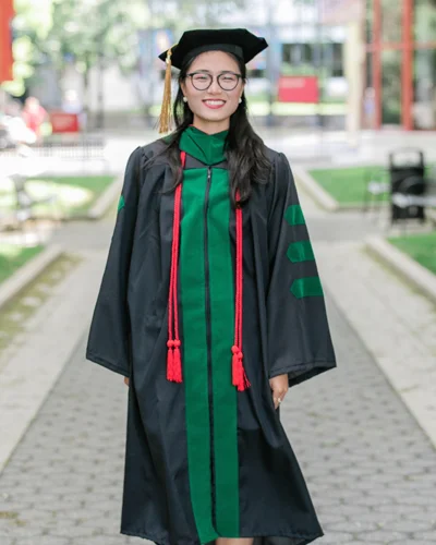 Hanna Kim in graduation robes standing in PCOM Philadelphia campus courtyard