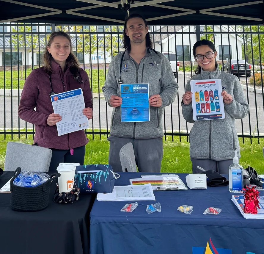 PCOM medical students smile while posing with health education flyers at a community event at Cobbs Creek Foundation