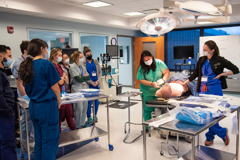 Medical students observe as a fellow student practices surgical techniques