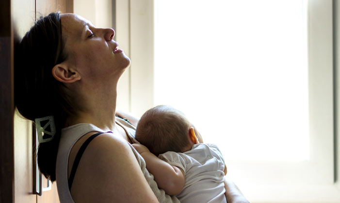 Mother lying on floor with newborn looking depressed and exhausted