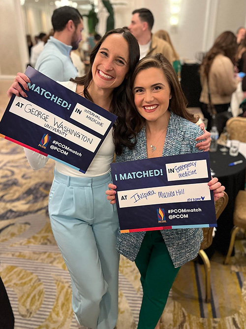 PCOM DO students Katie O'Shea and Jordan Selep smile and hold up their match day signs