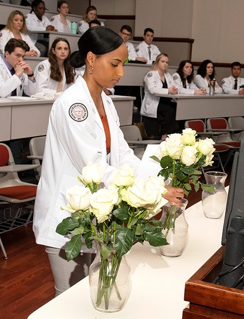 PCOM medical student arranges flowers to honor individuals who donated their bodies for medical learning.