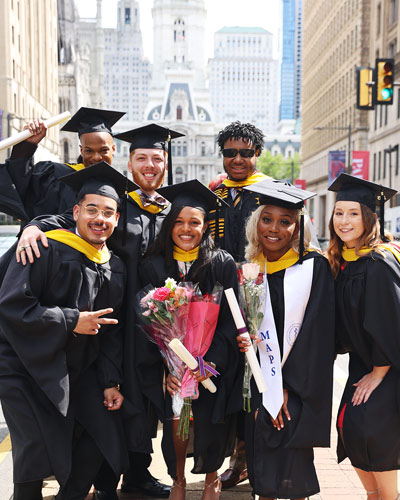 PCOM biomed student smile in their caps and gowns on Broad Street in Philadelphia