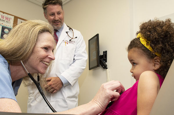 PCOM primary care physicians smile and examine a child during a doctor visit