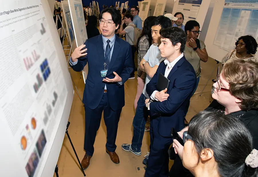 A PCOM student presents his research poster to participants during PCOM Research Day 2024