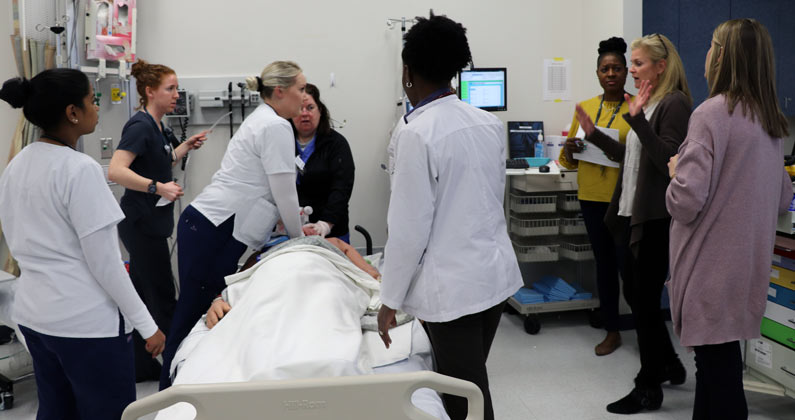 PCOM medical and psychology students work with Villanova nursing students around a mock patient in a mock emergency care room.