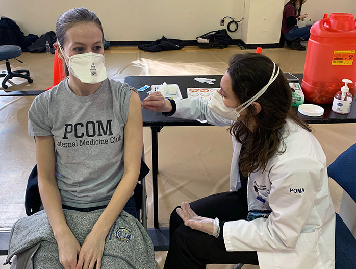 Med student Briana Krewson (DO `23) administers a COVID-19 vaccine shot at the PCOM Student-Run Clinic in Philadelphia.