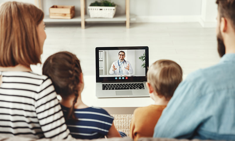 A young family meets with a doctor via a video call during a telehealth appointment