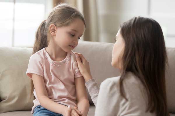 A sad-looking female child experiencing holiday stress is comforted by an adult female.