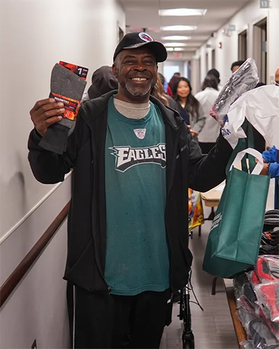 Smiling man holds up warm-weather clothing items he received from Community Days event