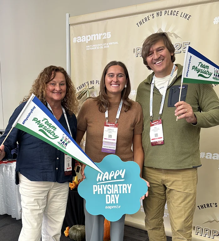 Gabrielle Horchos (DO ’26) stands with her parents holding signs celebrating physiatrists day
