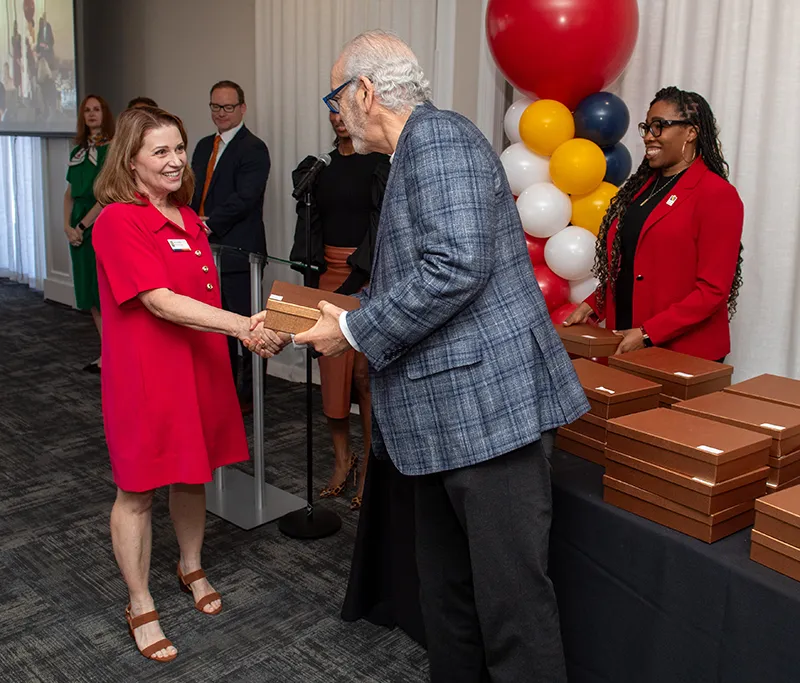 PCOM President Dr. Jay Feldstein and other presenters smile and present gifts to award recipients
