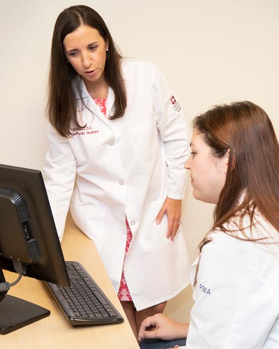 Beth Vitucci, DO, course director for the Medical Spanish elective, works with a student at a computer