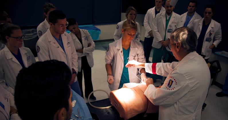 Dr. Arthur Sesso teaching general surgery practices to a group of students in PCOM's surgery simulation lab.