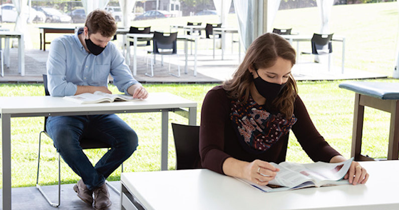 Med students wear face masks and read text books at outdoor study spaces on PCOM's Philadelphia campus.