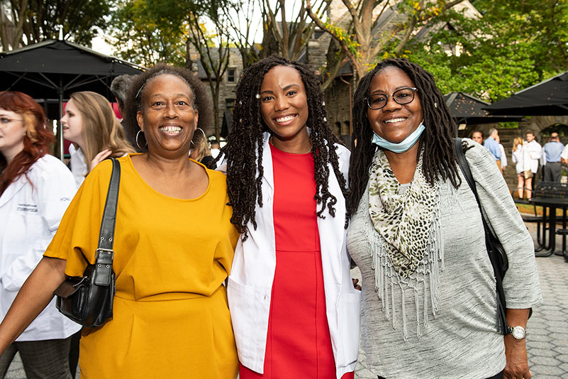 A member of the PCOM DO Class of 2025 smiles with her family during the white coat ceremony