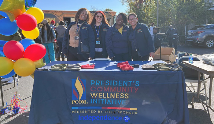 PCOM staff smile at a health information table at CWI Community Health Day in North Philly