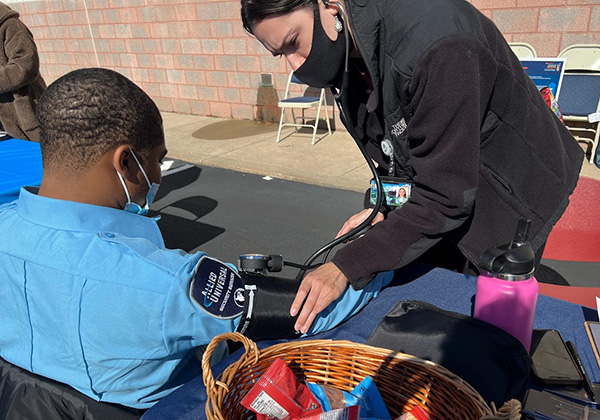 A PCOM med student provides a blood pressure screening outside at the health event in North Philly