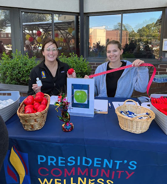 Medical students smile at a table as they interact with Park Tower residents at PCOM's Community Day