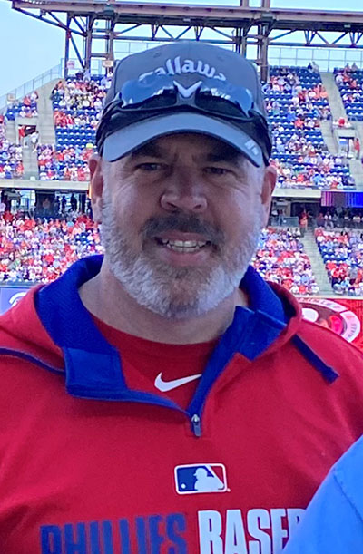 PCOM's Chief Information Officer Rick Smith, MBA, smiles in Phillies gear at Citizens Bank Park