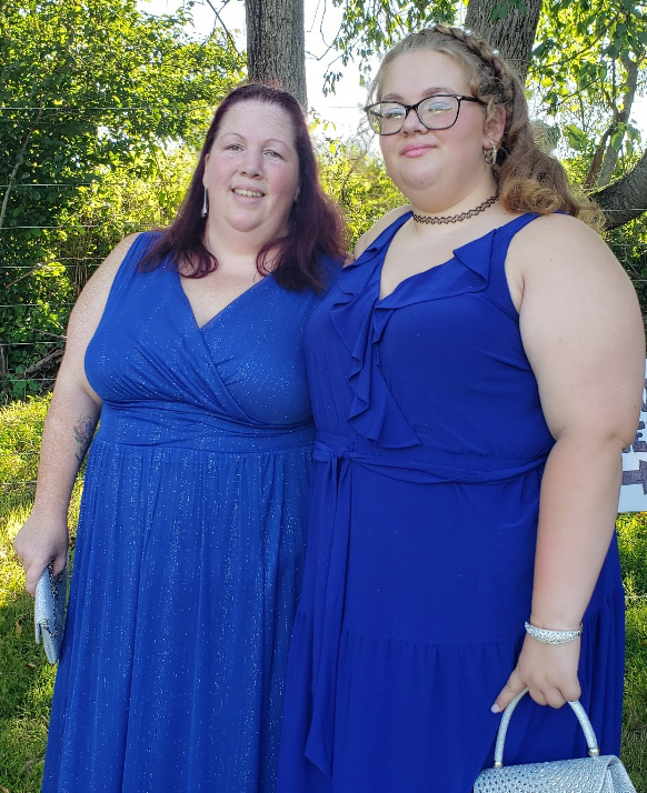PCOM's Heather Donahue smiling with her daughter wearing blue dresses outdoors