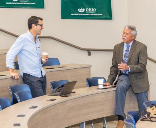 Neurological disease experts Kevin Zwezdaryk, PhD, and Brian Balin, PhD, talk in a lecture hall during the AlzPI x PCOM Symposium
