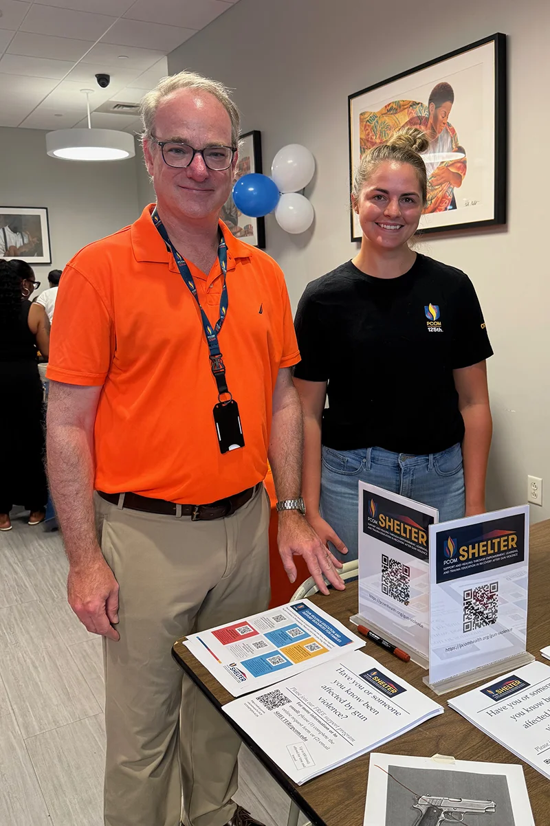 PCOM professor and SHELTER program co-director Erik Langenau, DO, MS, MAPP smiles at an informational gun violence resources table during a Philly event