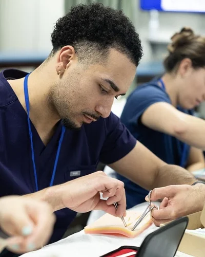 Romeo Mays (DO '27) using a suture practice kit