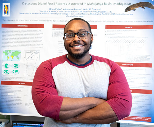 Cabrini student Brian Fuller in front of his research poster about lungfish fossils