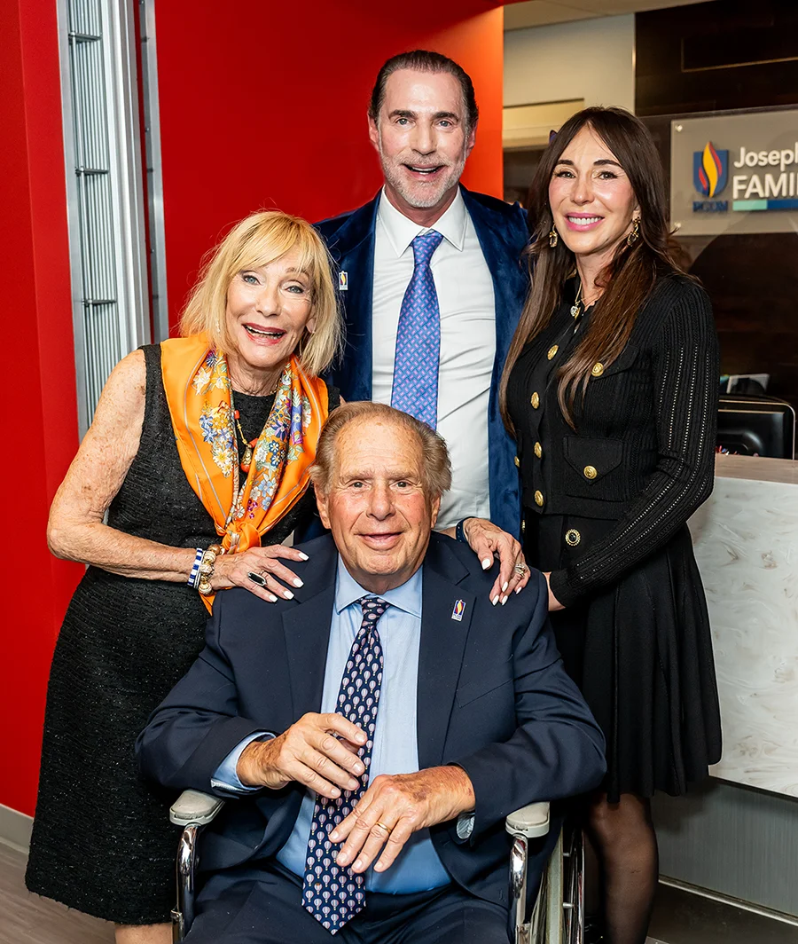Joseph M. Hassman, DO '65, and his family smile for a photo during a ribbon cutting ceremony