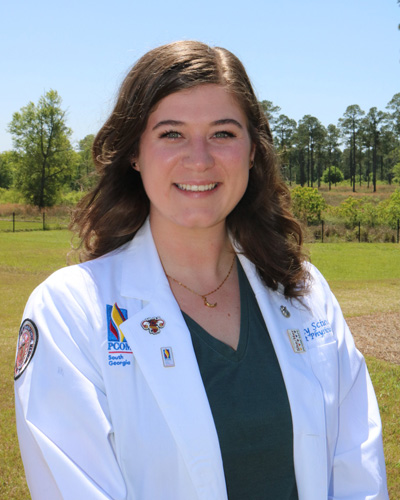 PCOM South Georgia osteopathic medical student Destiny Sciuva smiling on campus and wearing her student physician white coat