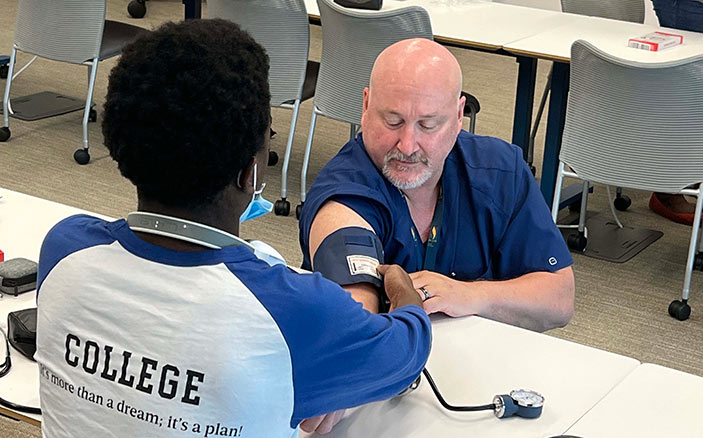 PCOM faculty member teaches a Dougherty high schooler how to take blood pressure readings