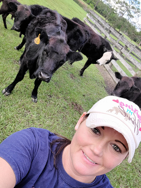 Heidi takes a selfie with a group of her black angus cows